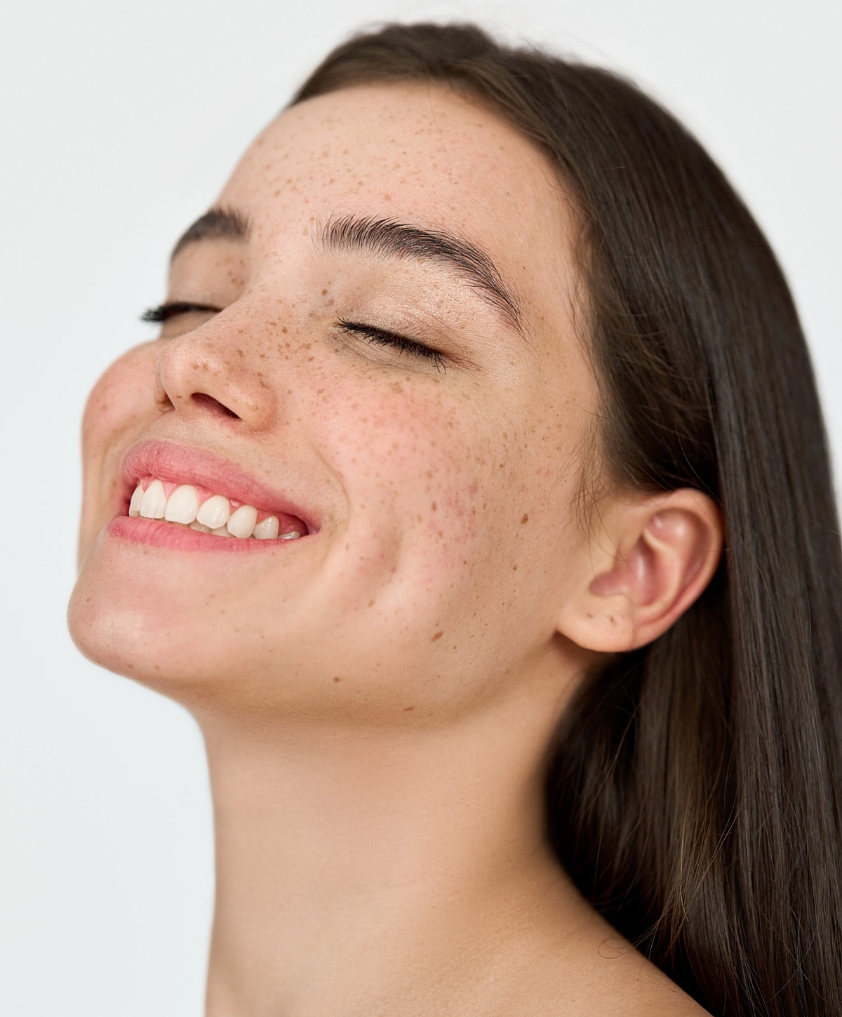 Smiling young woman with freckles and closed eyes.