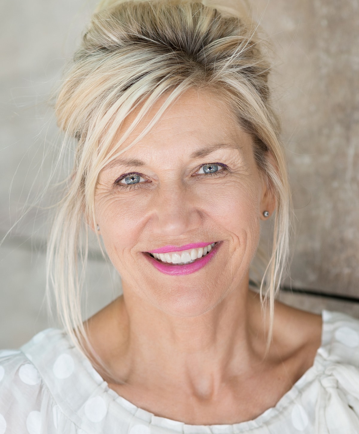 Smiling woman with blonde hair and pink lips.