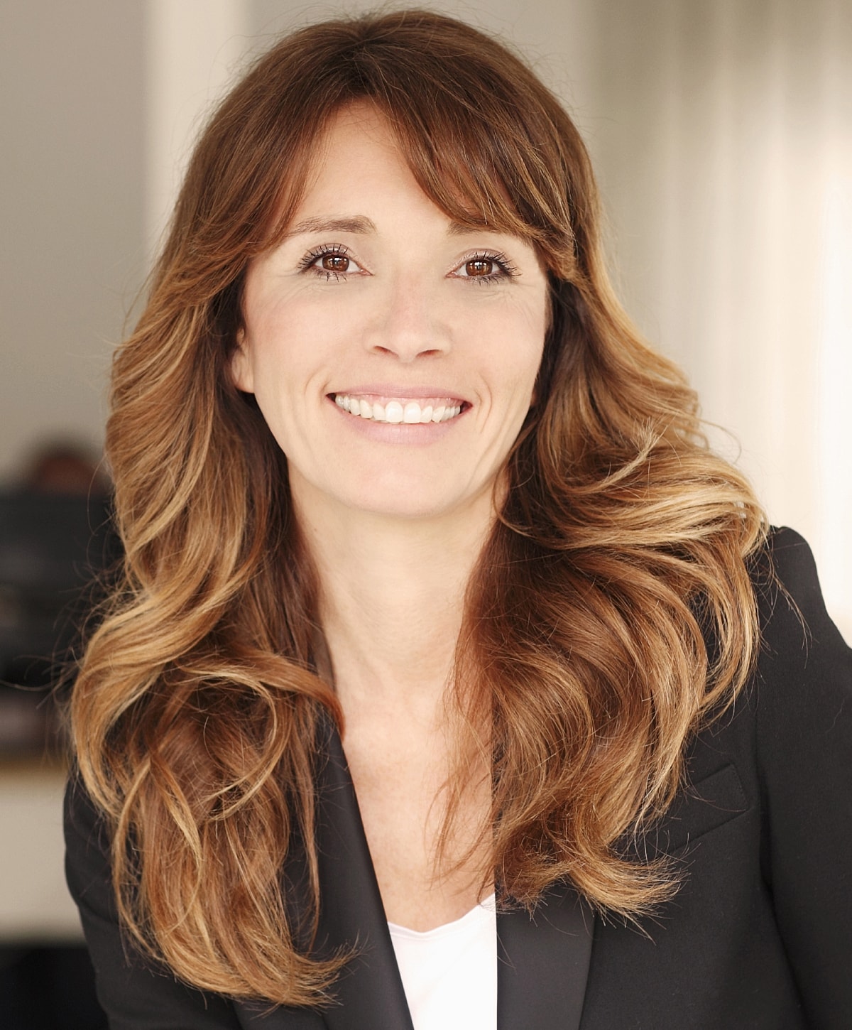 Smiling woman with long, wavy brown hair.
