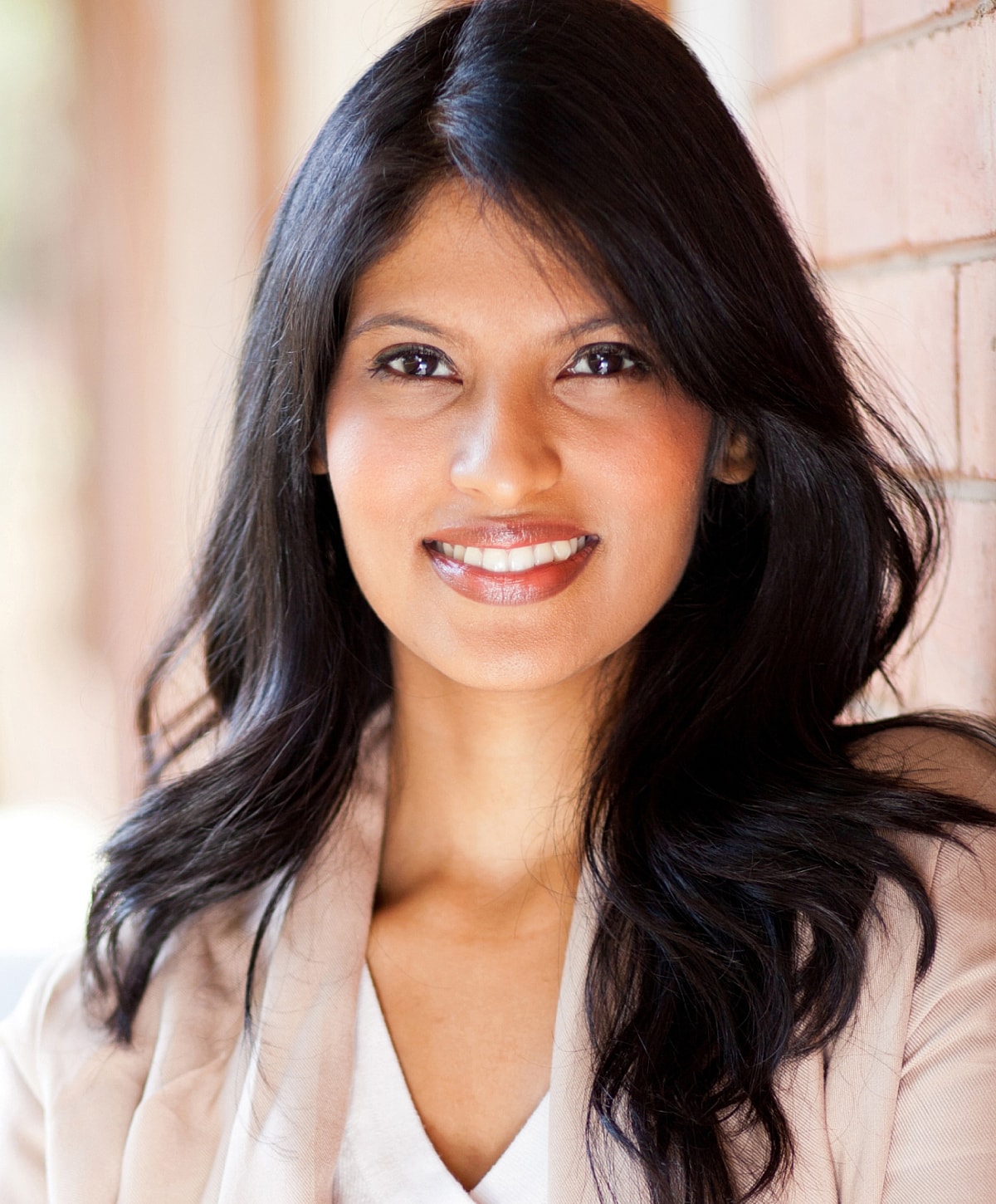 Smiling woman with long black hair indoors.