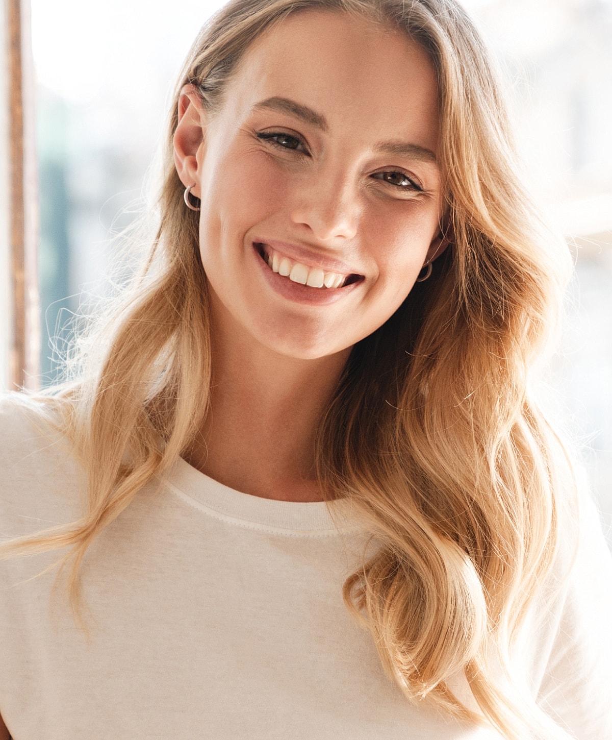 Smiling woman with long blonde hair indoors.