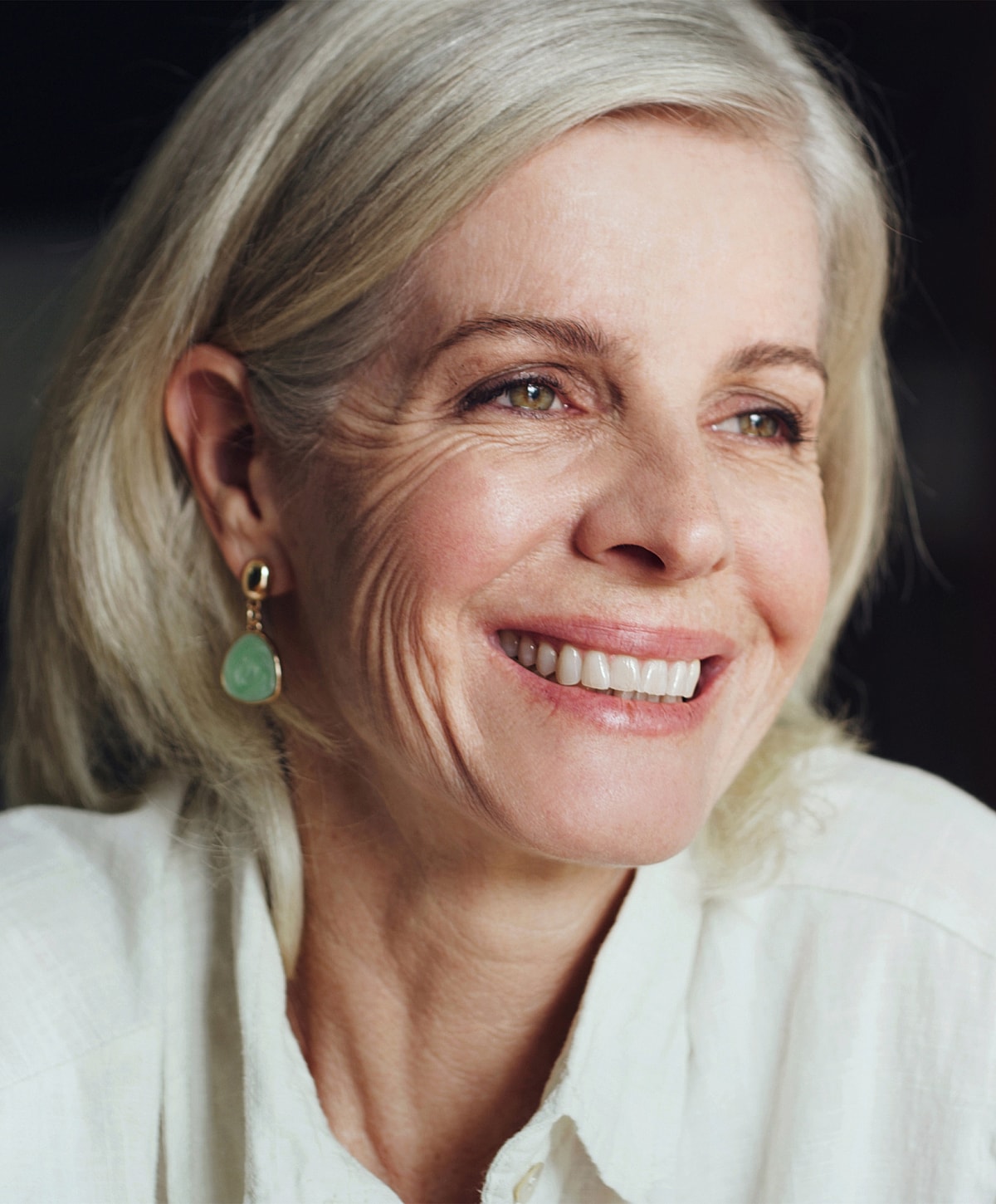 Smiling older woman with light hair and earrings.