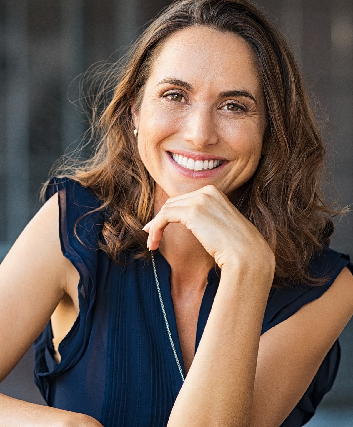Smiling woman resting chin on hand outdoors.