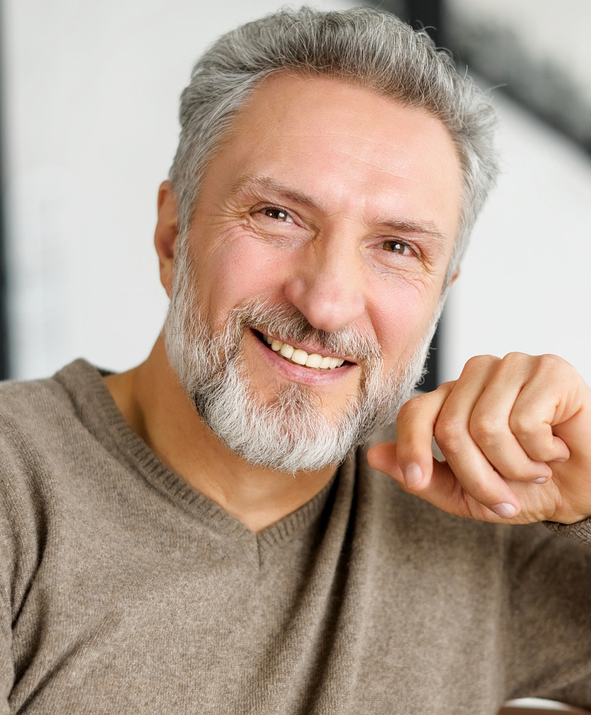 Smiling older man with a beard and sweater.