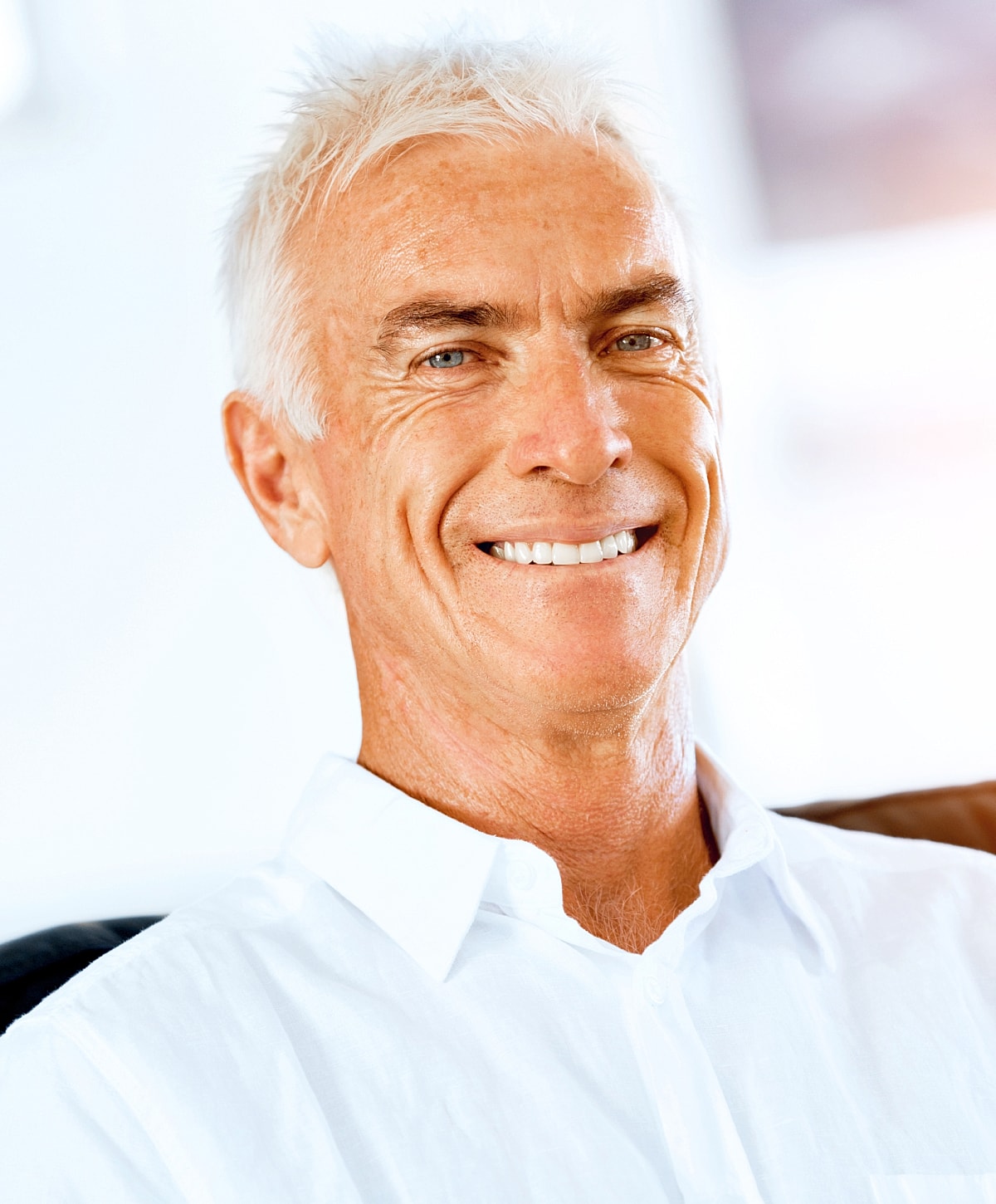 Smiling older man in white shirt indoors.