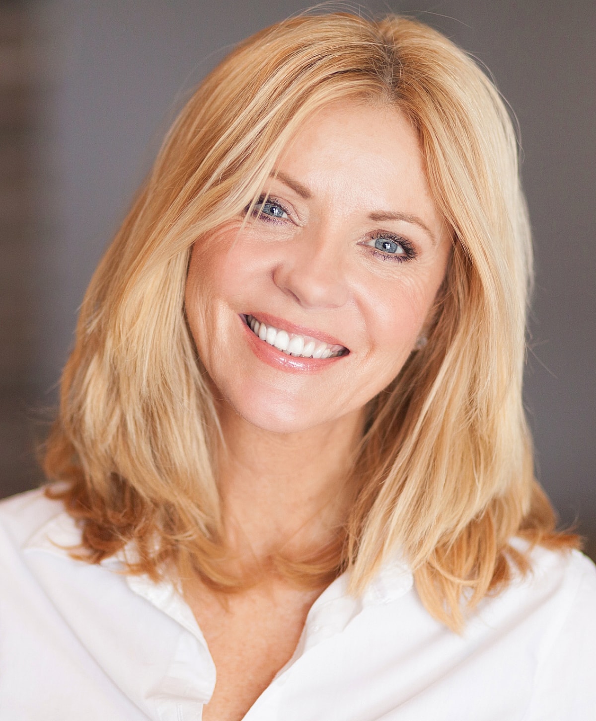 Smiling woman with blonde hair and white shirt.