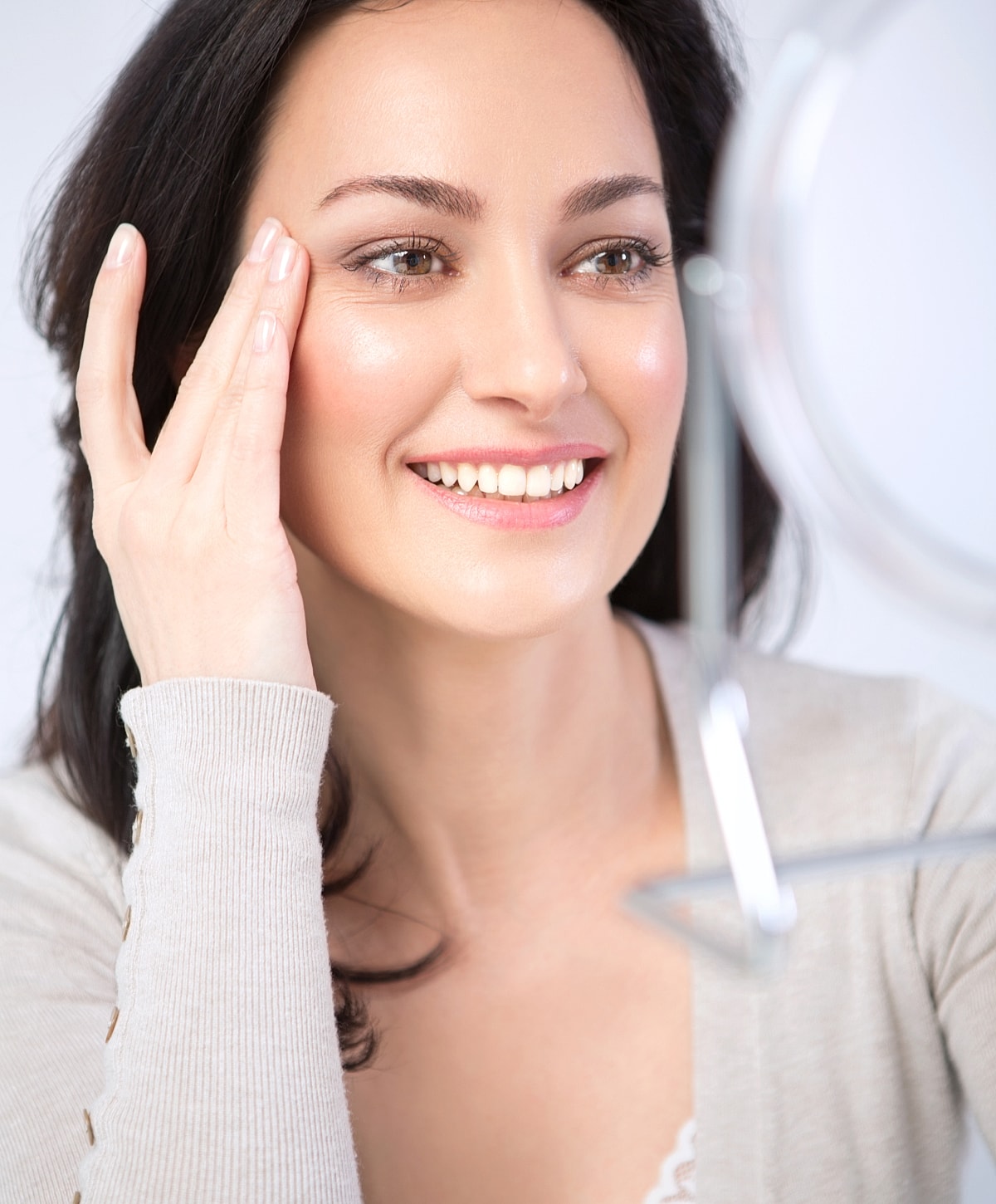 Smiling woman touching her face in mirror.