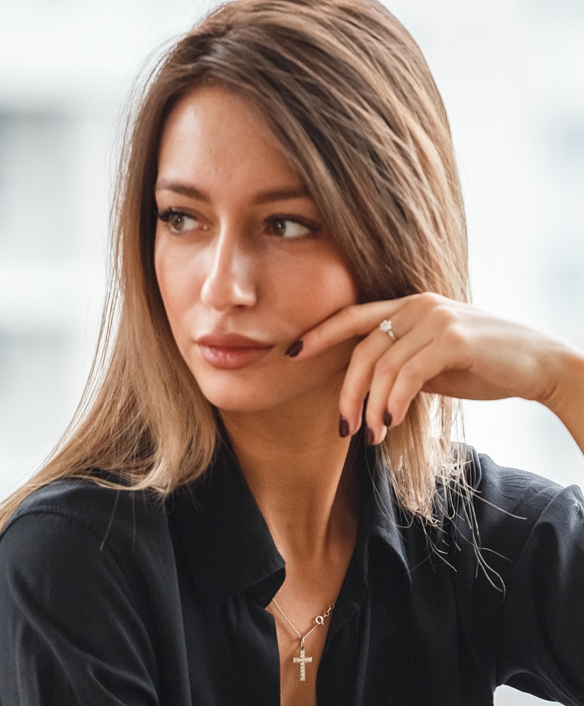 Woman with long hair and jewelry in a black shirt.