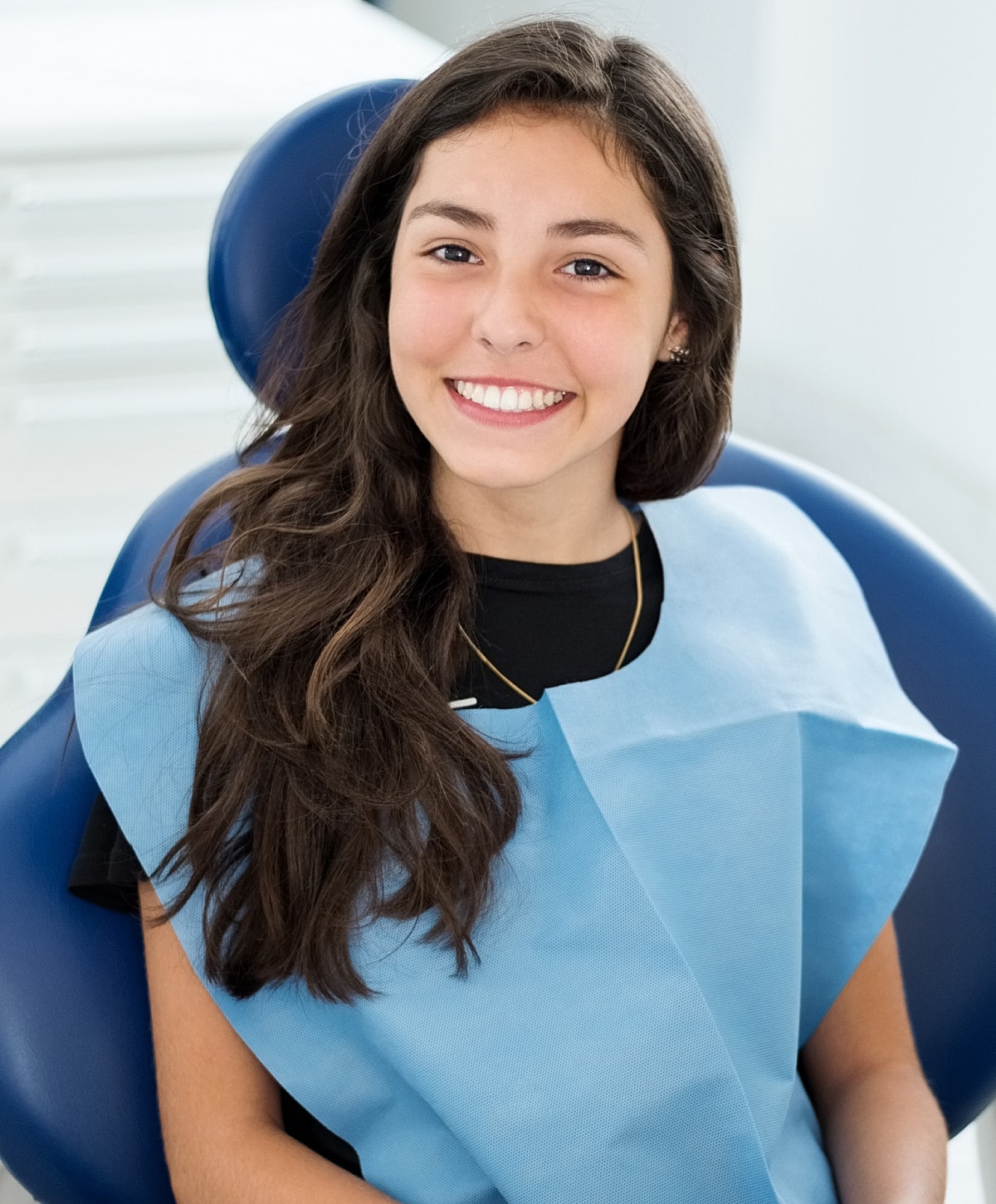 Smiling patient in dental chair wearing bib.
