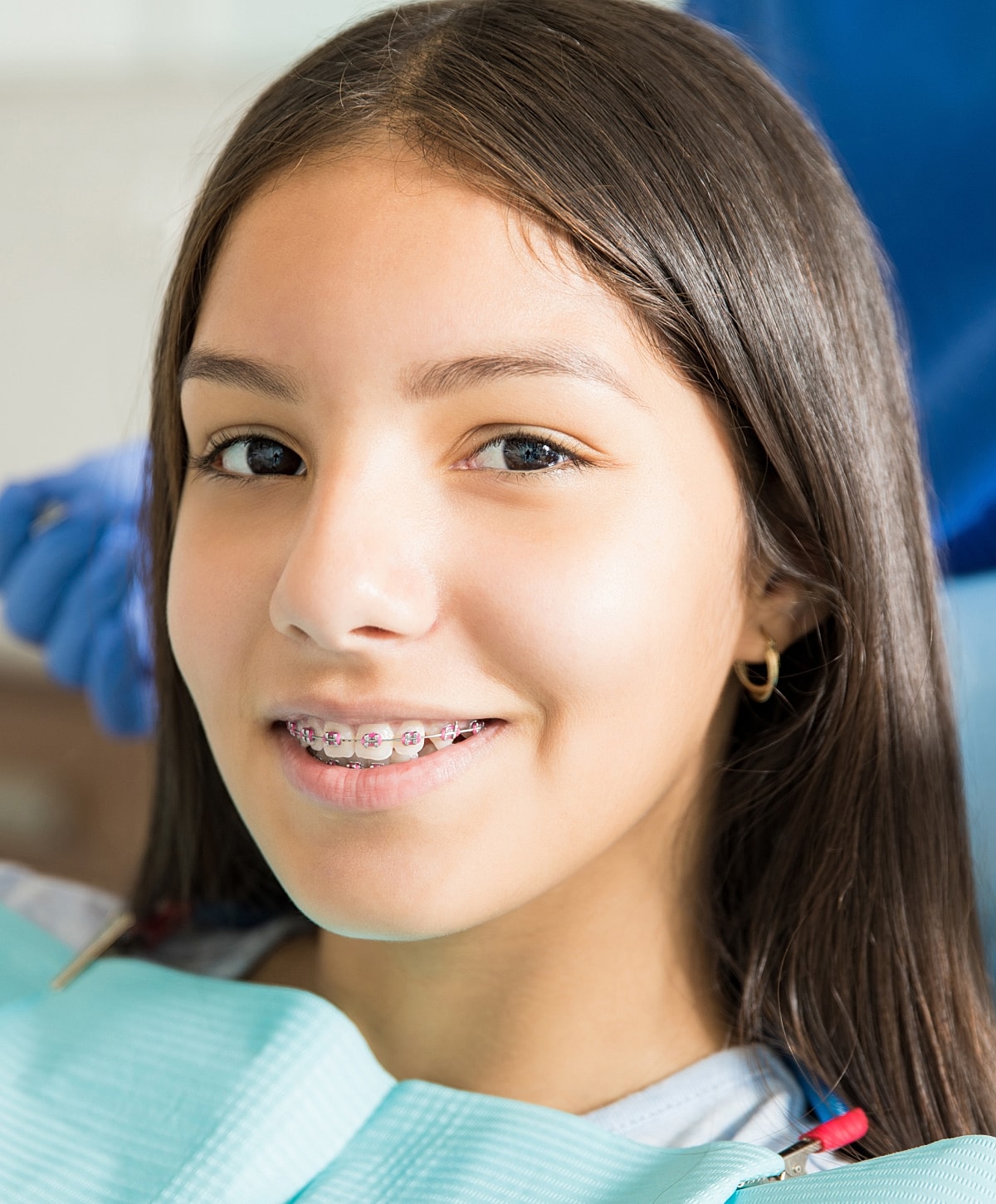 Girl smiling with braces in dental setting.