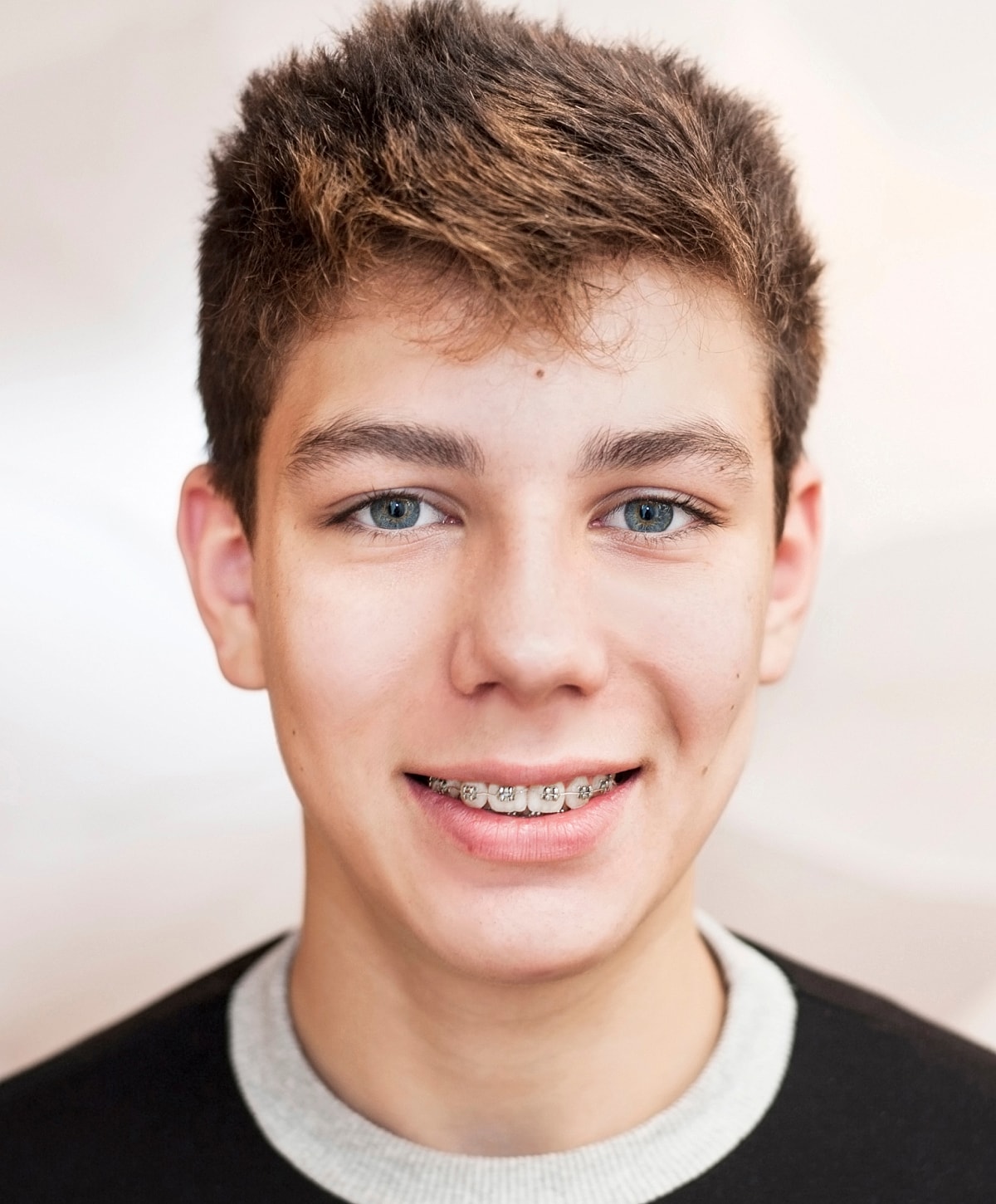 Smiling teenager with braces and blue eyes.