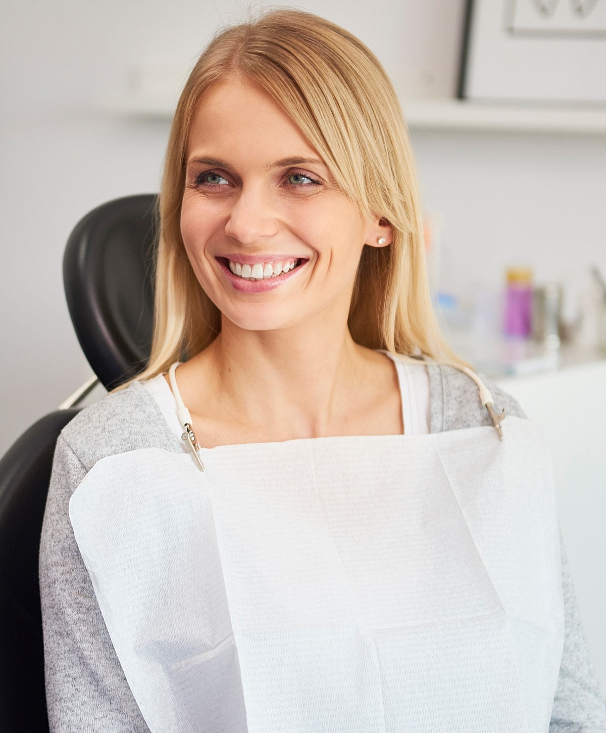 Smiling woman in dental office wearing bib.