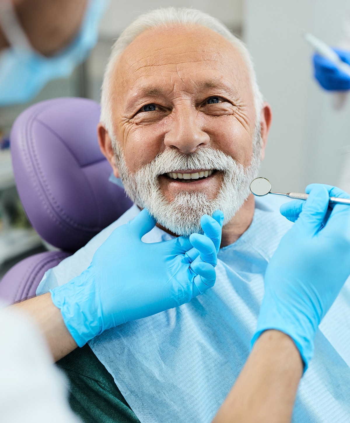 Senior man smiling in dental chair during checkup.
