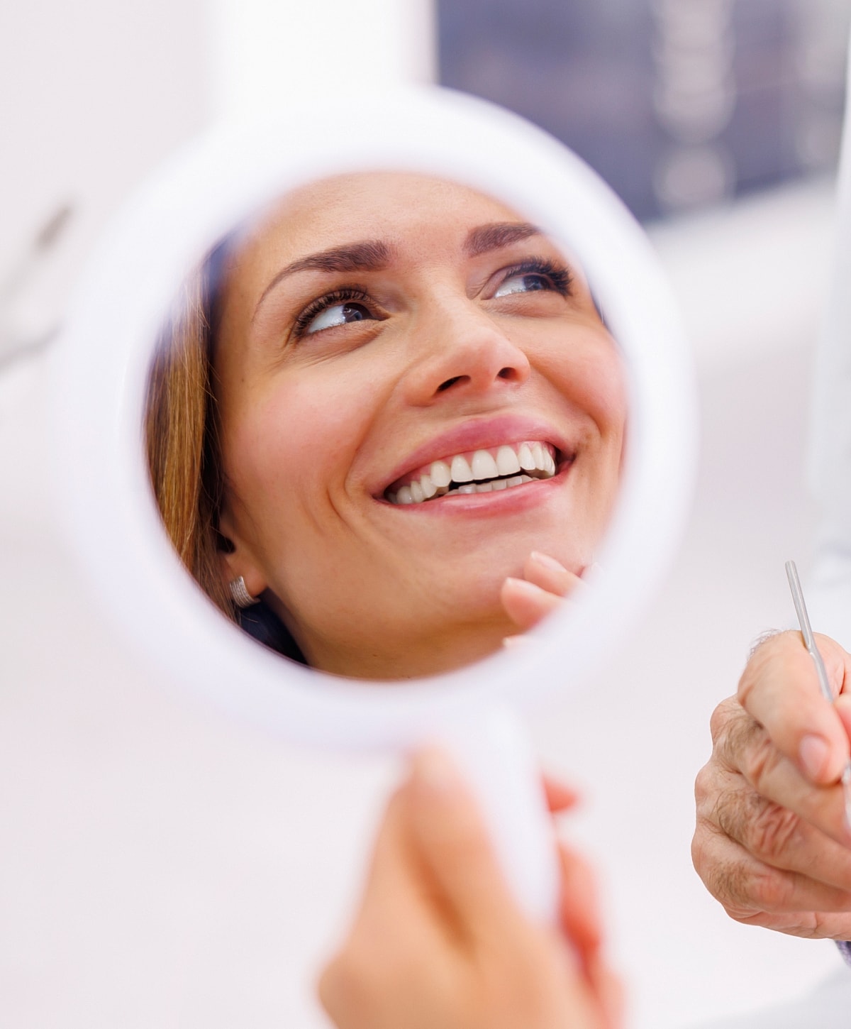 Smiling woman looking in a handheld mirror.