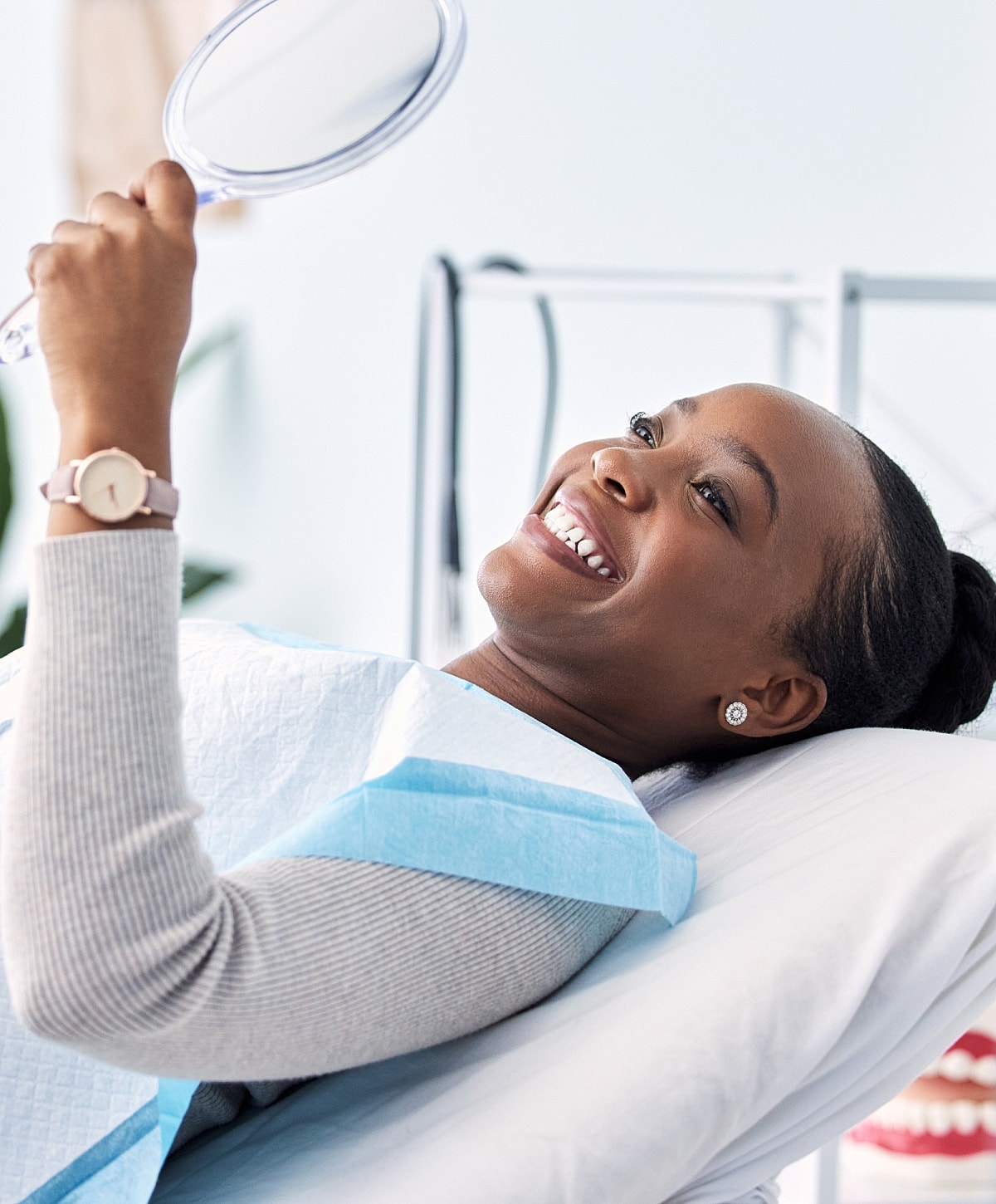 Smiling patient holding a dental mirror.