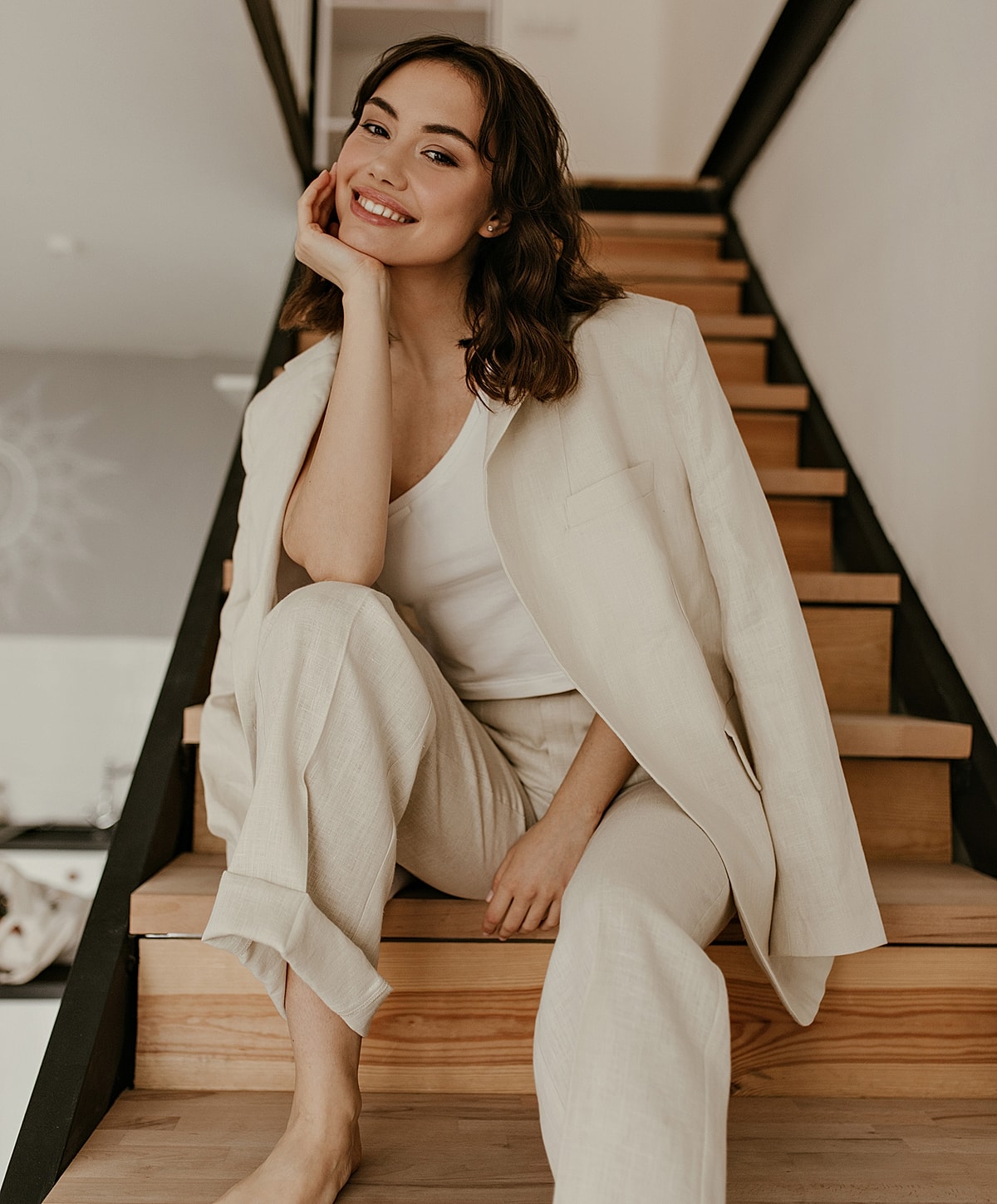Woman smiling in stylish beige outfit on steps.