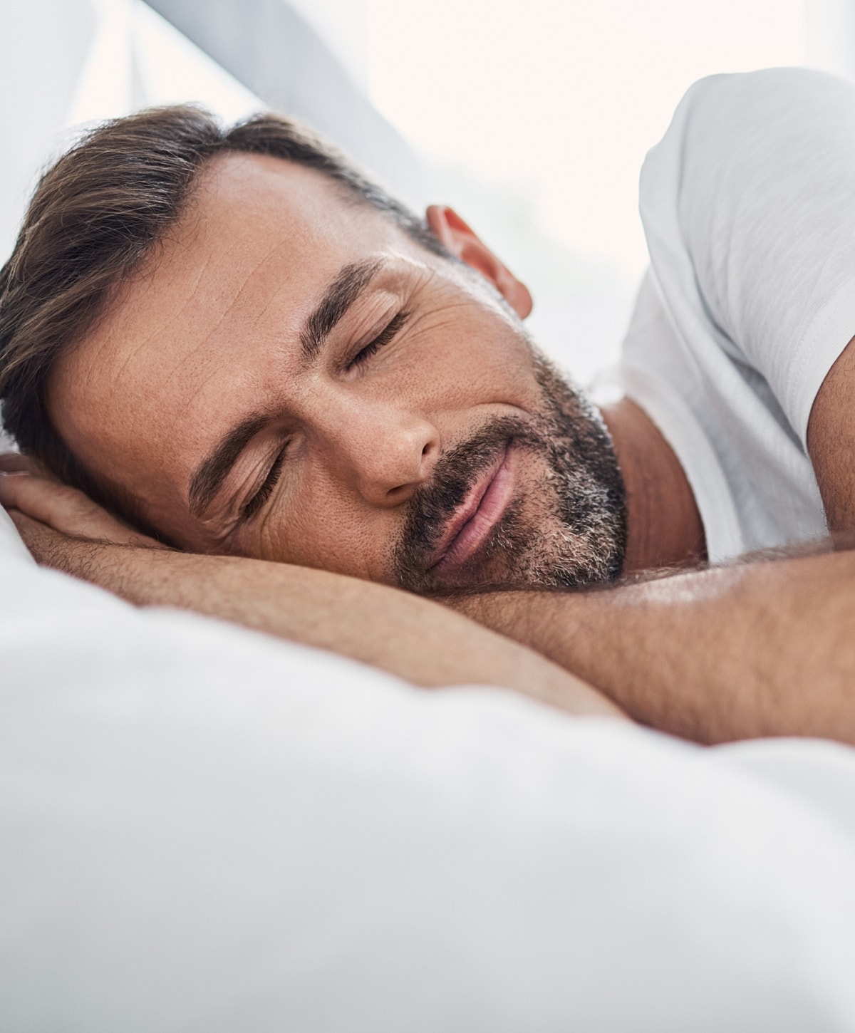Man sleeping peacefully on a white pillow.