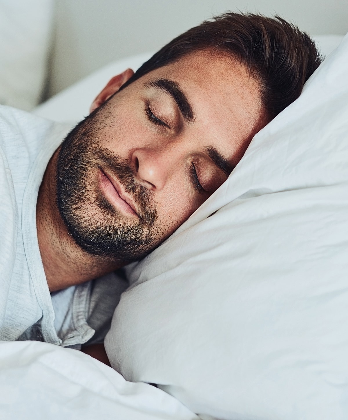 Man sleeping peacefully on white pillows.