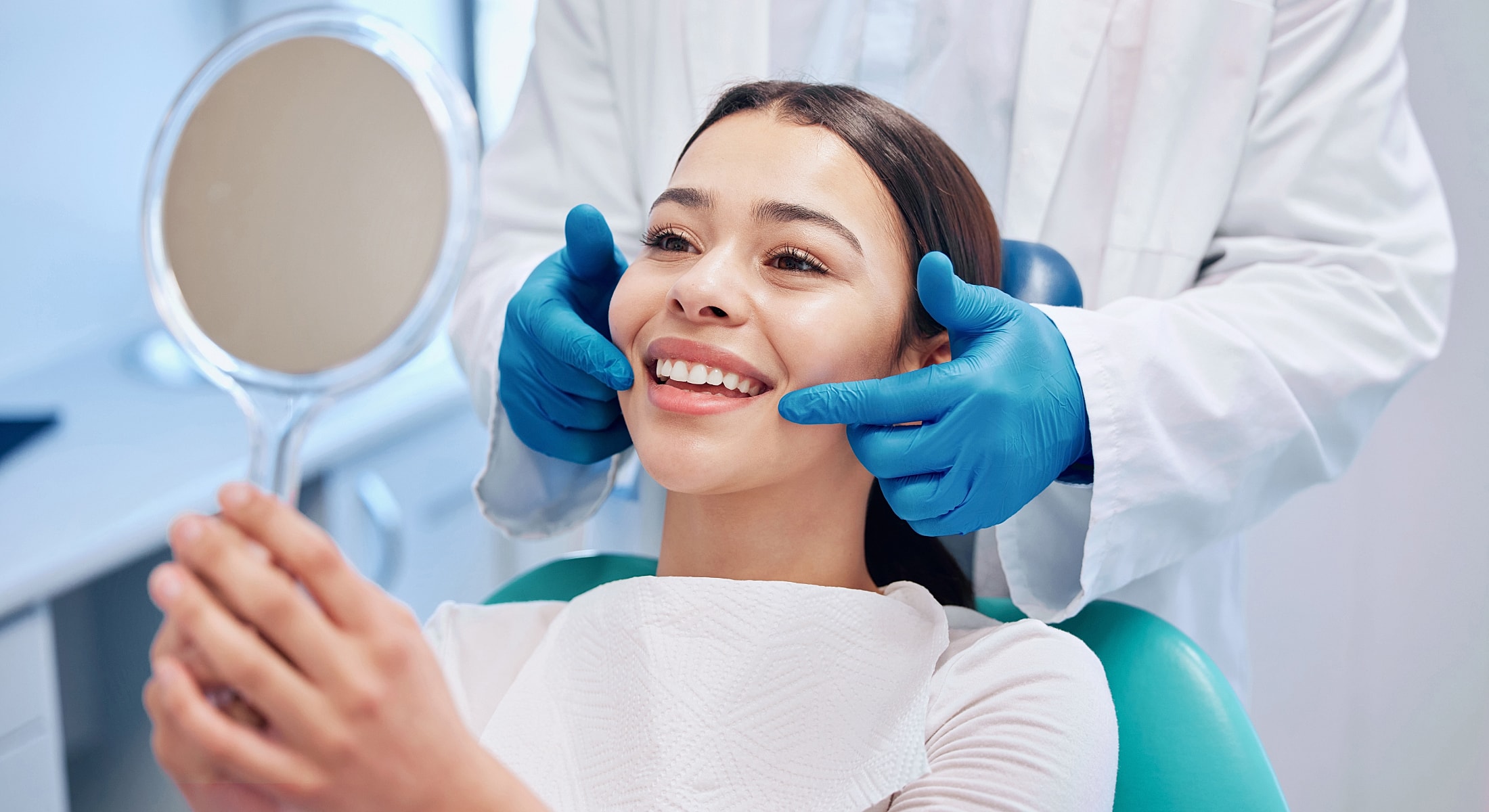 Patient smiling at mirror in dental office.